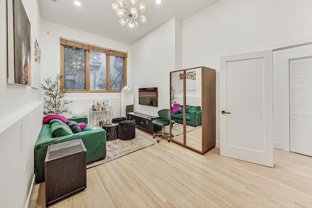 sitting room featuring an inviting chandelier, light hardwood / wood-style floors, and lofted ceiling