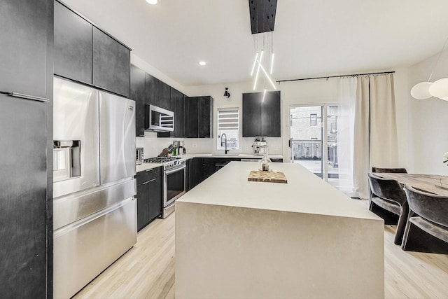 kitchen featuring appliances with stainless steel finishes, a center island, sink, and light hardwood / wood-style floors