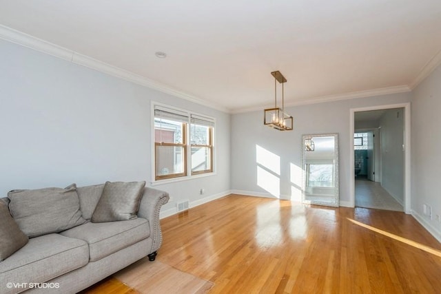 living room featuring an inviting chandelier, ornamental molding, and light hardwood / wood-style floors