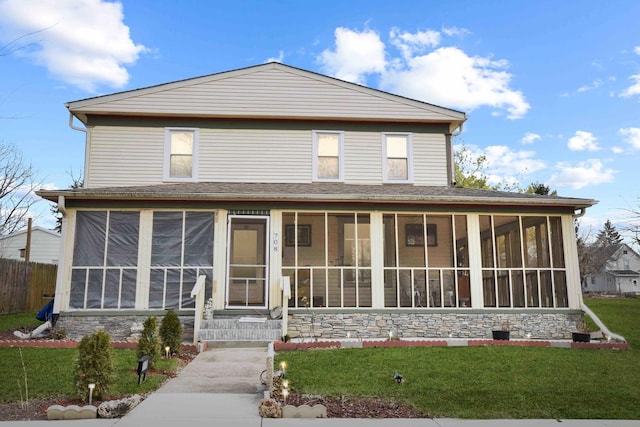 view of front of property featuring a front lawn and a sunroom