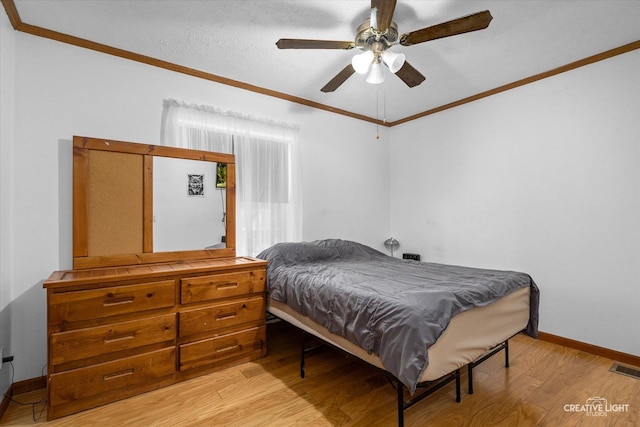 bedroom featuring a textured ceiling, ornamental molding, ceiling fan, and light wood-type flooring