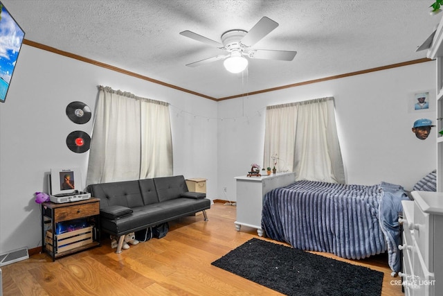 bedroom featuring ceiling fan, wood-type flooring, ornamental molding, and a textured ceiling