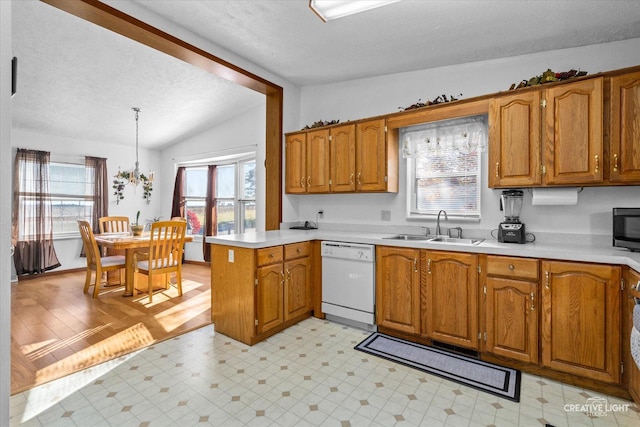 kitchen featuring lofted ceiling, sink, a textured ceiling, white dishwasher, and kitchen peninsula