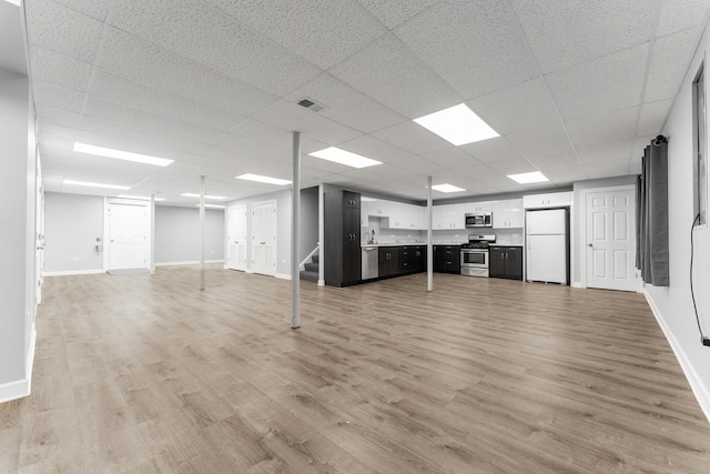 basement with a drop ceiling, light wood-type flooring, and white refrigerator