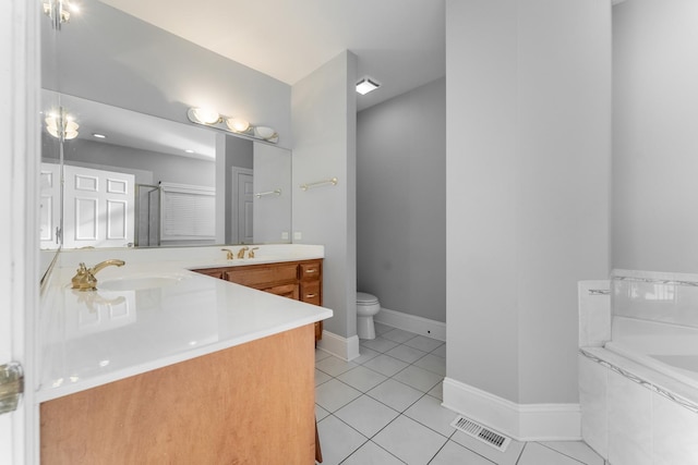 bathroom with tile patterned flooring, vanity, a relaxing tiled tub, and toilet