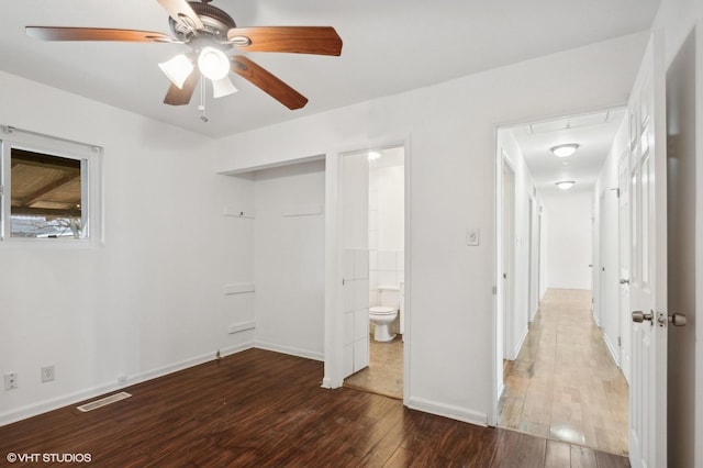 unfurnished bedroom with ensuite bath, dark wood-type flooring, and ceiling fan