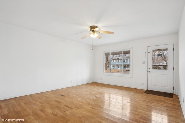 empty room with plenty of natural light, ceiling fan, and light wood-type flooring