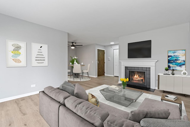 living room with ceiling fan, a fireplace, and light wood-type flooring