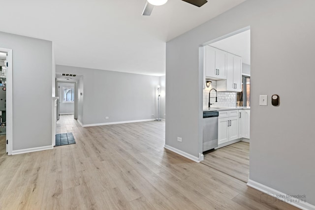 unfurnished living room with sink, light hardwood / wood-style flooring, and ceiling fan