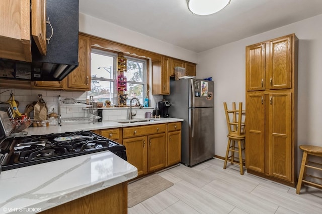 kitchen with gas stove, sink, stainless steel refrigerator, and decorative backsplash