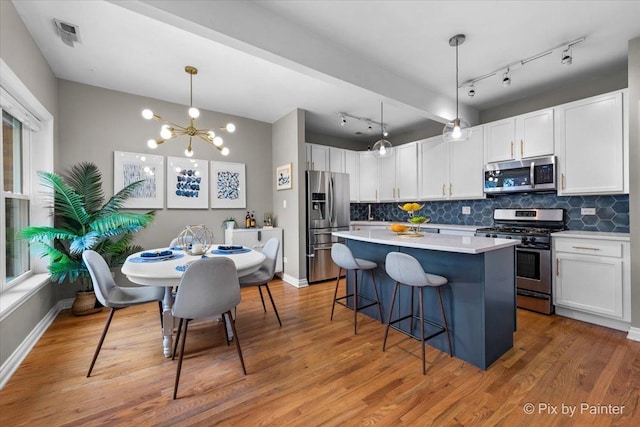 kitchen featuring a center island, a breakfast bar area, decorative backsplash, appliances with stainless steel finishes, and light wood-style floors