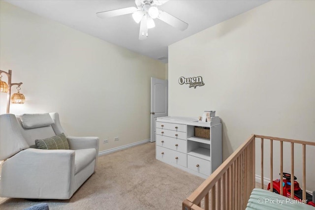 bedroom with light carpet, a crib, a ceiling fan, and baseboards