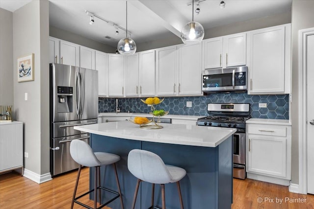 kitchen with stainless steel appliances, a kitchen breakfast bar, light countertops, and light wood finished floors