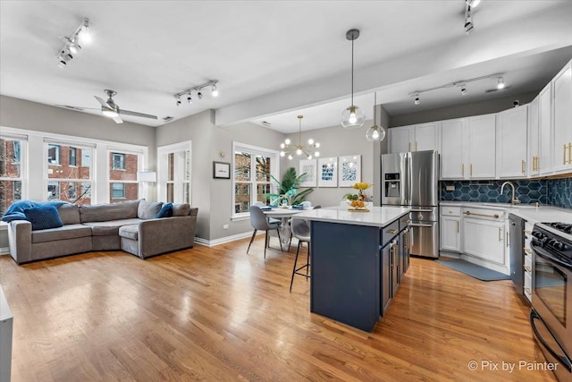 kitchen with appliances with stainless steel finishes, light wood-style floors, a kitchen breakfast bar, and a kitchen island