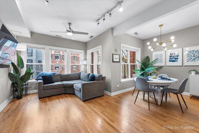 living area with visible vents, light wood-style flooring, track lighting, baseboards, and ceiling fan with notable chandelier