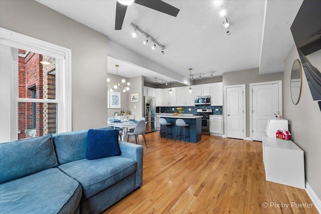 living area with ceiling fan, light wood-type flooring, and track lighting