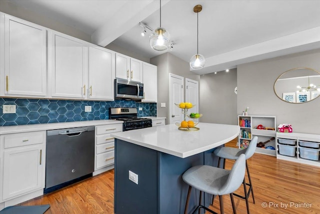 kitchen with a breakfast bar area, light wood finished floors, light countertops, backsplash, and appliances with stainless steel finishes