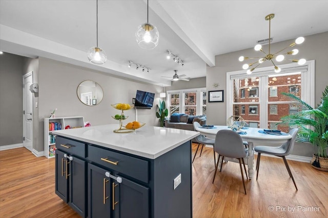 kitchen with light countertops, light wood finished floors, a ceiling fan, and pendant lighting