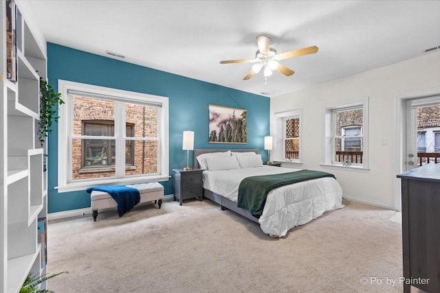 carpeted bedroom featuring a ceiling fan, multiple windows, visible vents, and baseboards