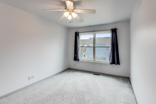 spare room with carpet floors, baseboards, visible vents, and ceiling fan