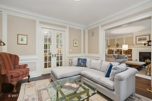 living room with wood-type flooring, ornamental molding, a premium fireplace, and french doors