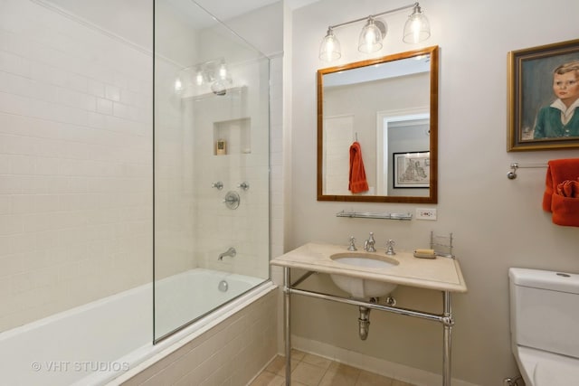 full bathroom with tile patterned flooring, sink, tiled shower / bath combo, and toilet