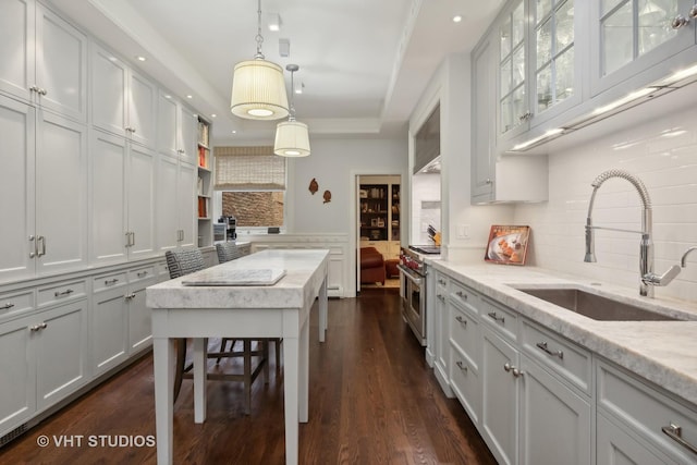 kitchen featuring white cabinetry, a tray ceiling, sink, and range with two ovens