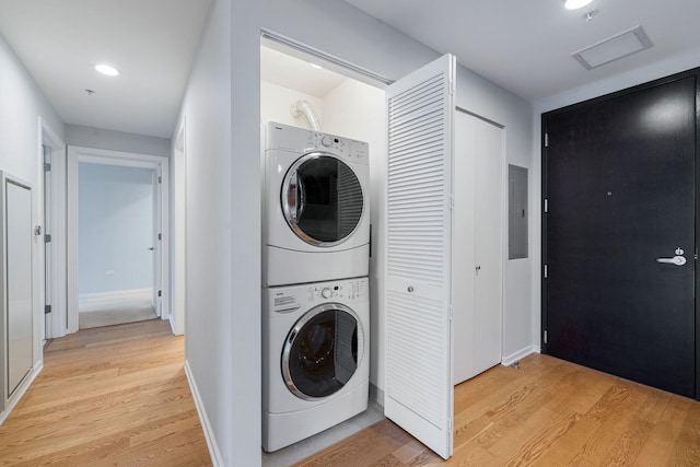 laundry room with stacked washer and clothes dryer, visible vents, light wood-type flooring, laundry area, and electric panel