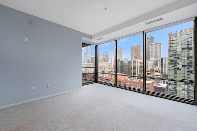 empty room with expansive windows, a view of city, baseboards, and carpet flooring