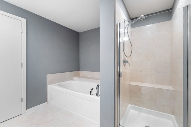 bathroom featuring tile patterned floors, a stall shower, a garden tub, and baseboards