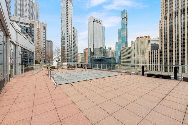 view of patio / terrace featuring a tennis court, a view of city, and fence