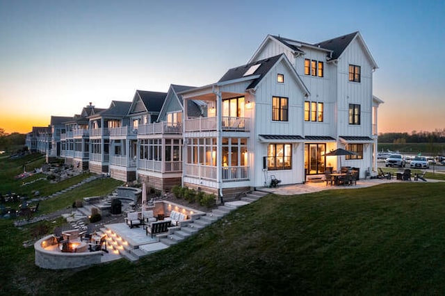 back house at dusk with an outdoor fire pit, a yard, and a patio