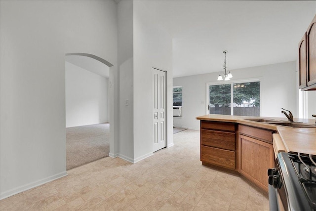 kitchen with sink, hanging light fixtures, gas range oven, light carpet, and an inviting chandelier