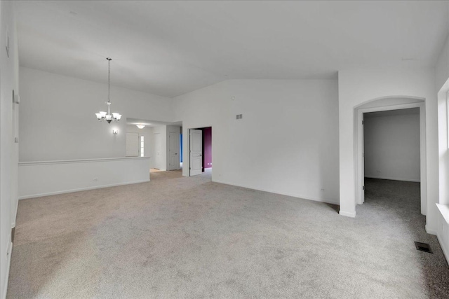 carpeted empty room with lofted ceiling and a chandelier