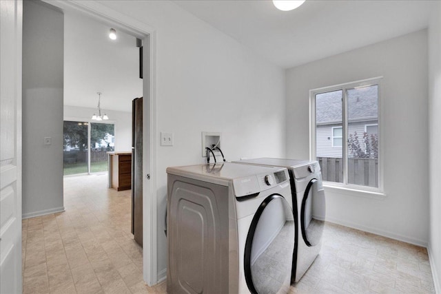 laundry area featuring washer and clothes dryer, a chandelier, and plenty of natural light