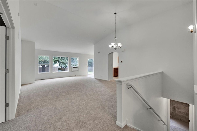 unfurnished living room with vaulted ceiling, light colored carpet, and a chandelier