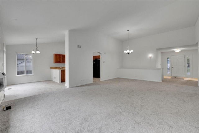 unfurnished living room with light carpet, a notable chandelier, and lofted ceiling