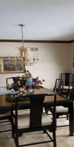 dining space with crown molding and a chandelier