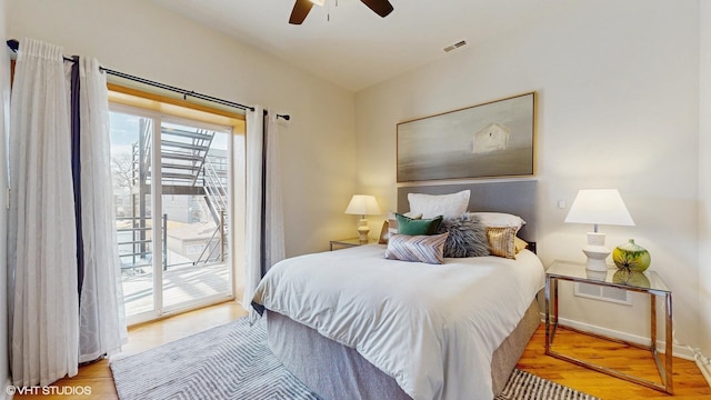 bedroom featuring a ceiling fan, access to outside, visible vents, and wood finished floors