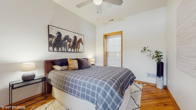 bedroom with a ceiling fan, visible vents, baseboards, and wood finished floors