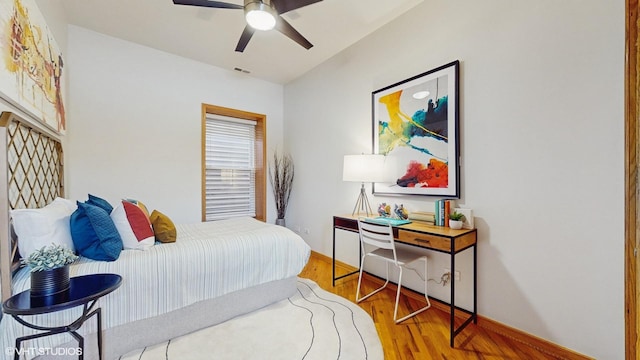 bedroom featuring a ceiling fan, visible vents, baseboards, and wood finished floors