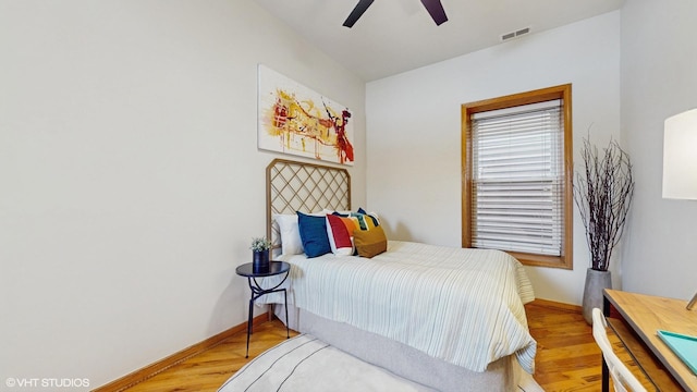 bedroom with ceiling fan, wood finished floors, visible vents, and baseboards