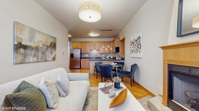 living area featuring light wood-type flooring, a fireplace, and baseboards