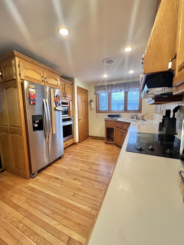 kitchen with tasteful backsplash, sink, light wood-type flooring, stainless steel refrigerator with ice dispenser, and black electric cooktop