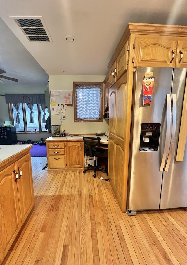 kitchen featuring ceiling fan, built in desk, light hardwood / wood-style floors, and stainless steel fridge with ice dispenser