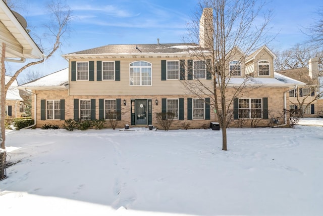 view of front of home featuring brick siding and a chimney