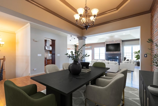 dining space featuring an inviting chandelier, decorative columns, a tray ceiling, and ornamental molding