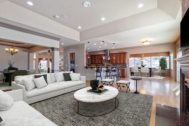 living area with ornamental molding, a raised ceiling, a notable chandelier, and recessed lighting