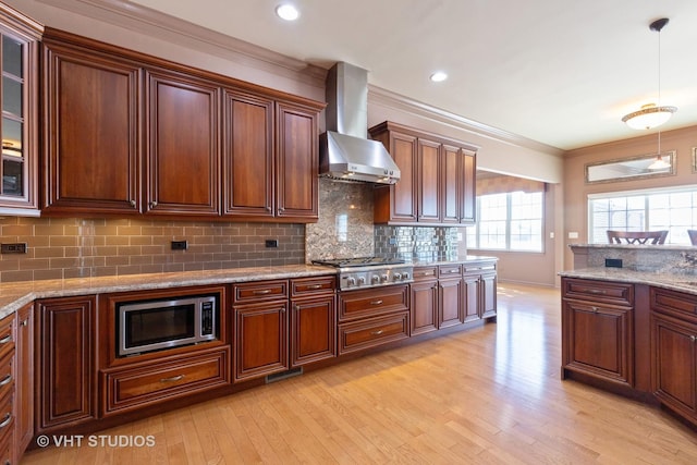 kitchen featuring light wood-style flooring, appliances with stainless steel finishes, wall chimney range hood, tasteful backsplash, and crown molding