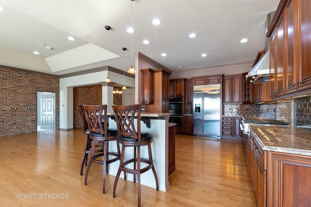 kitchen with built in refrigerator, dobule oven black, light wood-style flooring, and a peninsula